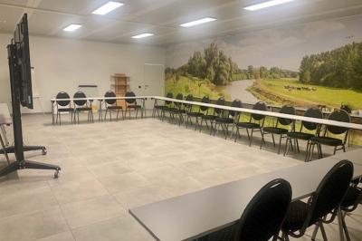 Salle de réunion avec des rangées de chaises face à un écran de projection, sous un plafond en briques apparentes.
