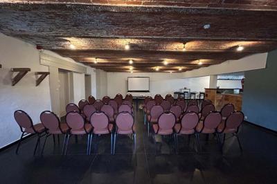 Salle de réunion avec des rangées de chaises face à un écran de projection, sous un plafond en briques apparentes.