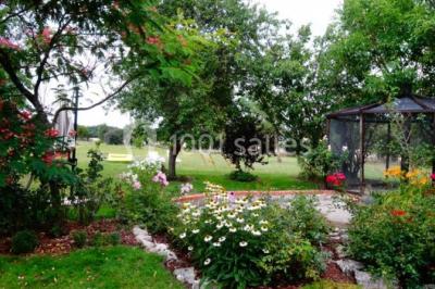 Tente rouge et blanche abritant des tables dressées avec nappes et décorations pour un repas en extérieur.