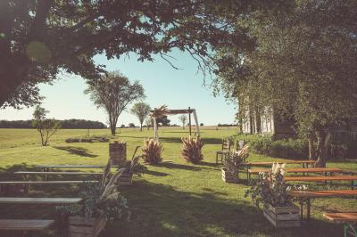 Tente rouge et blanche abritant des tables dressées avec nappes et décorations pour un repas en extérieur.
