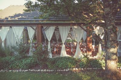 Tente rouge et blanche abritant des tables dressées avec nappes et décorations pour un repas en extérieur.