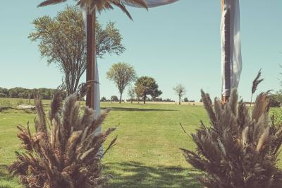 Tente rouge et blanche abritant des tables dressées avec nappes et décorations pour un repas en extérieur.