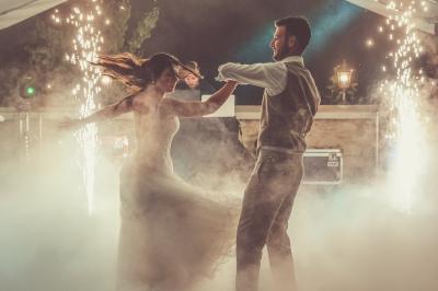 Tente rouge et blanche abritant des tables dressées avec nappes et décorations pour un repas en extérieur.