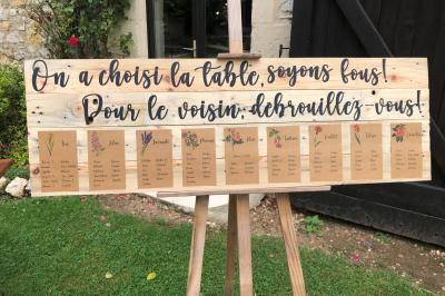 Tente rouge et blanche abritant des tables dressées avec nappes et décorations pour un repas en extérieur.