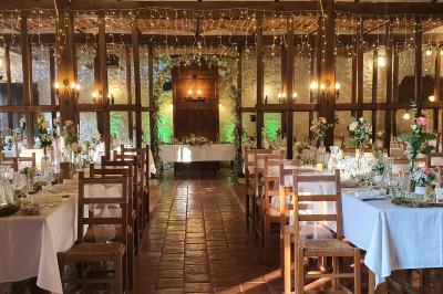Tente rouge et blanche abritant des tables dressées avec nappes et décorations pour un repas en extérieur.