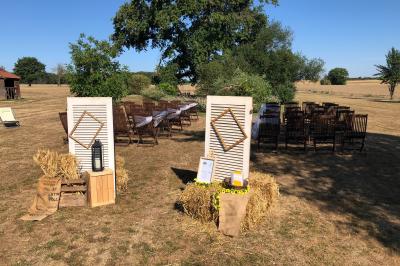 Tente rouge et blanche abritant des tables dressées avec nappes et décorations pour un repas en extérieur.