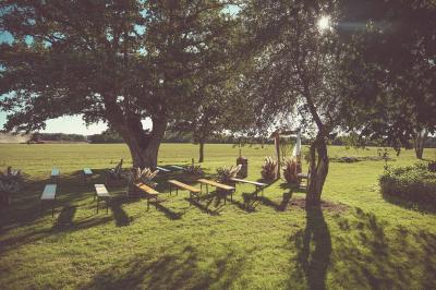Tente rouge et blanche abritant des tables dressées avec nappes et décorations pour un repas en extérieur.