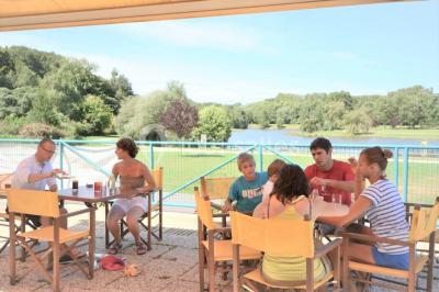 Deux personnes jouent au tennis sur un court extérieur entouré d'arbres par une journée ensoleillée.