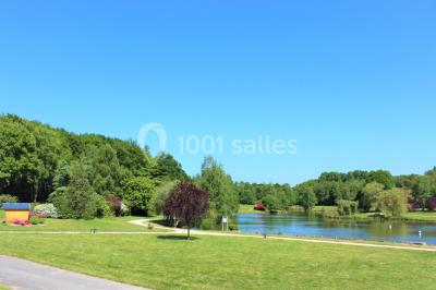 Deux personnes jouent au tennis sur un court extérieur entouré d'arbres par une journée ensoleillée.