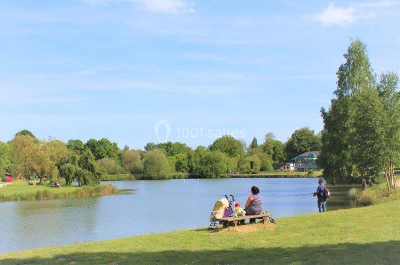 Location salle Merdrignac (Côtes-d'Armor) - Val de Landrouet #8 Deux personnes assises sur un banc près d'un lac entouré d'arbres, sous un ciel dégagé.