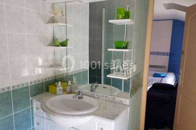 Allée rouge bordée de plantes et de panneaux, menant à une maison en pierre sous un ciel dégagé.