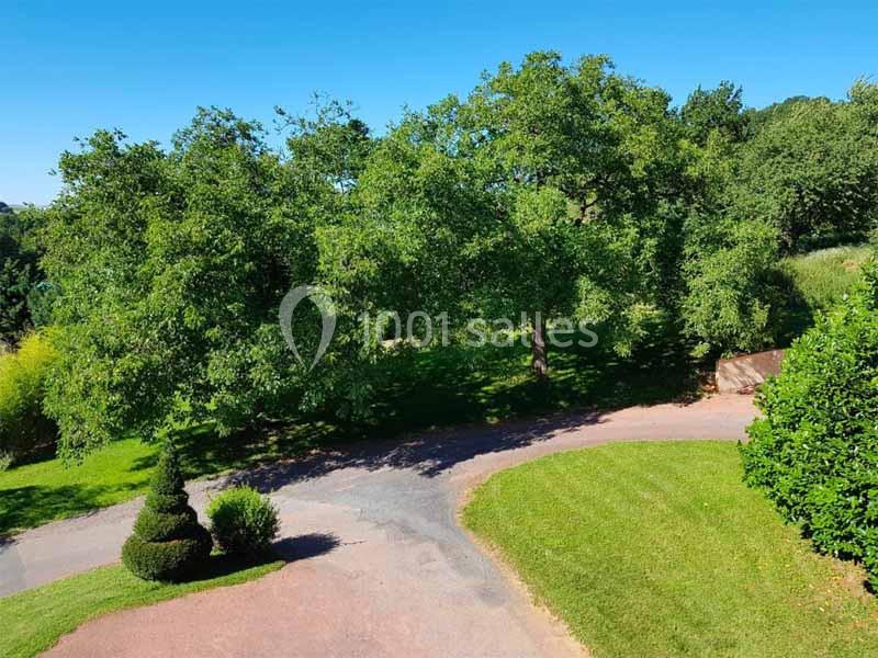 Allée sinueuse bordée de pelouses et d'arbres verdoyants sous un ciel bleu clair.