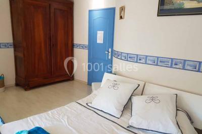 Allée rouge bordée de plantes et de panneaux, menant à une maison en pierre sous un ciel dégagé.