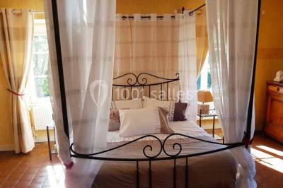 Allée rouge bordée de plantes et de panneaux, menant à une maison en pierre sous un ciel dégagé.