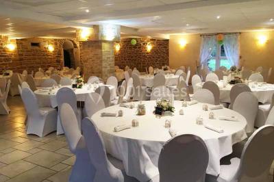 Allée rouge bordée de plantes et de panneaux, menant à une maison en pierre sous un ciel dégagé.