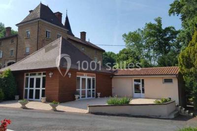 Allée rouge bordée de plantes et de panneaux, menant à une maison en pierre sous un ciel dégagé.