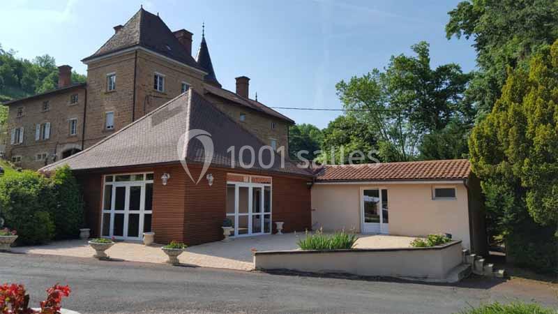 Bâtiment en pierre avec une extension moderne, entouré de verdure et d'une allée pavée.