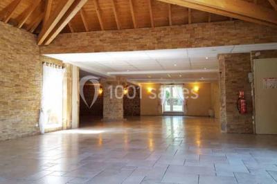 Allée rouge bordée de plantes et de panneaux, menant à une maison en pierre sous un ciel dégagé.