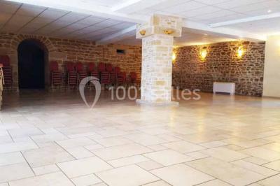 Allée rouge bordée de plantes et de panneaux, menant à une maison en pierre sous un ciel dégagé.