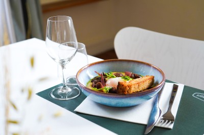Plantes d'intérieur variées dans des pots en verre et en métal doré, disposées sur une cheminée en marbre noir.