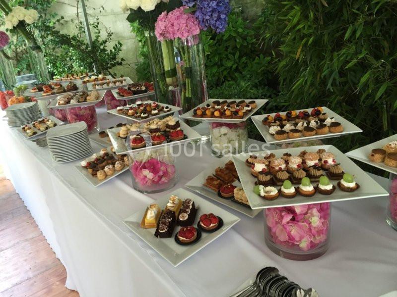 Table garnie de desserts variés présentés sur des assiettes blanches, entourée de décorations florales.