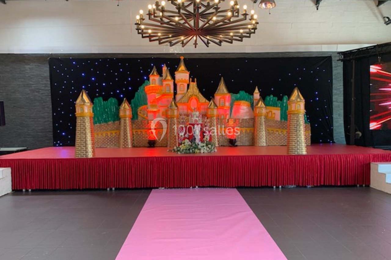 Décor de scène avec un château doré illuminé, fond étoilé et tapis rose menant à la scène.