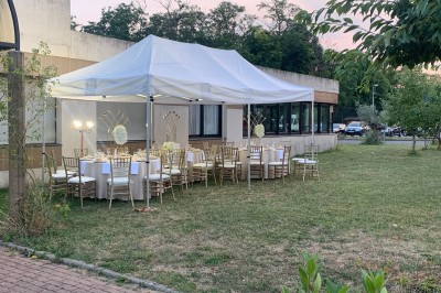 Salle décorée avec des tables rondes, nappes blanches et chaises rouges, prête pour un événement festif.