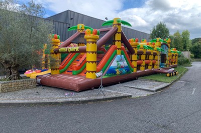 Salle décorée avec des tables rondes, nappes blanches et chaises rouges, prête pour un événement festif.