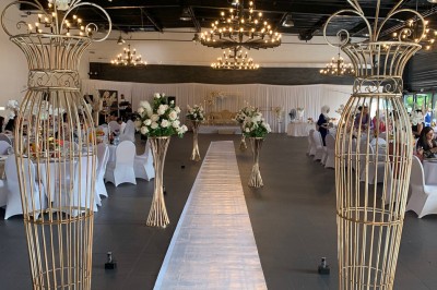 Salle décorée avec des tables rondes, nappes blanches et chaises rouges, prête pour un événement festif.