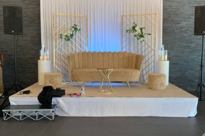 Salle décorée avec des tables rondes, nappes blanches et chaises rouges, prête pour un événement festif.