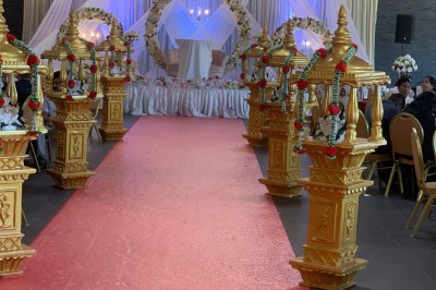 Salle décorée avec des tables rondes, nappes blanches et chaises rouges, prête pour un événement festif.