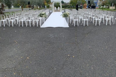 Salle décorée avec des tables rondes, nappes blanches et chaises rouges, prête pour un événement festif.