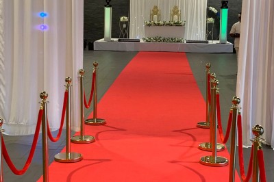 Salle décorée avec des tables rondes, nappes blanches et chaises rouges, prête pour un événement festif.