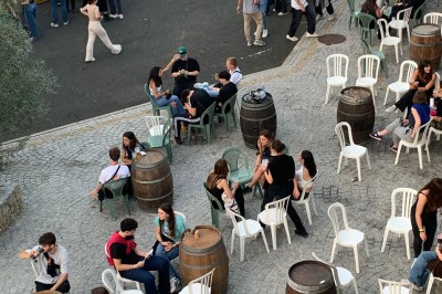 Salle décorée avec des tables rondes, nappes blanches et chaises rouges, prête pour un événement festif.