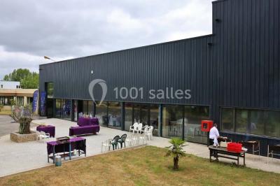 Salle de réception moderne avec tables hautes colorées, buffet en arrière-plan et éclairage suspendu.