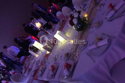 Salle de réception moderne avec tables hautes colorées, buffet en arrière-plan et éclairage suspendu.