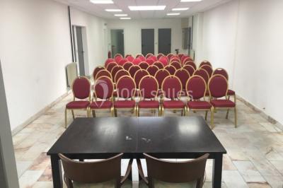 Salle de réception moderne avec tables hautes colorées, buffet en arrière-plan et éclairage suspendu.