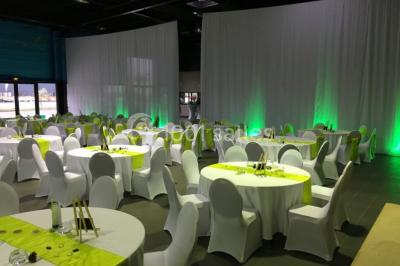 Salle de réception moderne avec tables hautes colorées, buffet en arrière-plan et éclairage suspendu.