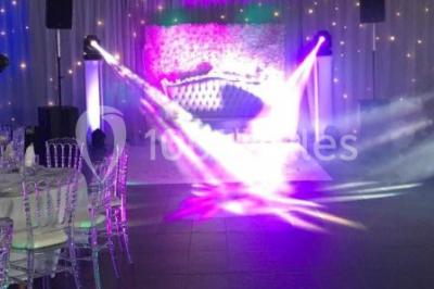 Salle de réception moderne avec tables hautes colorées, buffet en arrière-plan et éclairage suspendu.