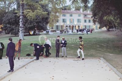 Vue aérienne d'une grande maison de style provençal avec des tables dressées pour un événement en extérieur.