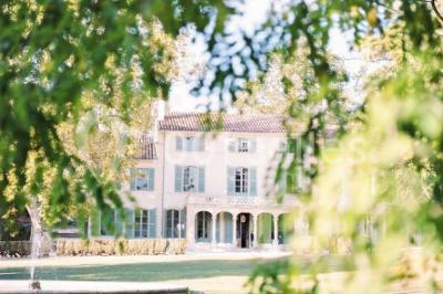 Vue aérienne d'une grande maison de style provençal avec des tables dressées pour un événement en extérieur.
