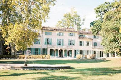 Vue aérienne d'une grande maison de style provençal avec des tables dressées pour un événement en extérieur.