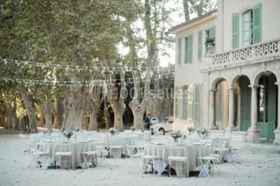 Vue aérienne d'une grande maison de style provençal avec des tables dressées pour un événement en extérieur.