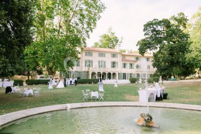 Vue aérienne d'une grande maison de style provençal avec des tables dressées pour un événement en extérieur.