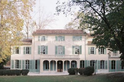 Vue aérienne d'une grande maison de style provençal avec des tables dressées pour un événement en extérieur.