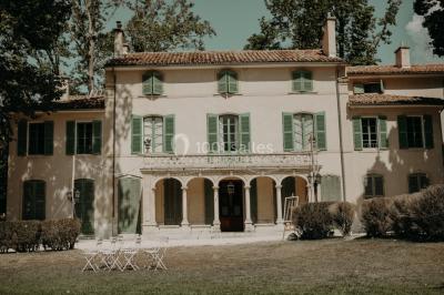 Vue aérienne d'une grande maison de style provençal avec des tables dressées pour un événement en extérieur.