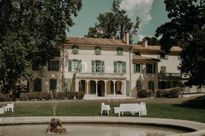 Vue aérienne d'une grande maison de style provençal avec des tables dressées pour un événement en extérieur.