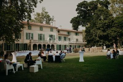 Vue aérienne d'une grande maison de style provençal avec des tables dressées pour un événement en extérieur.