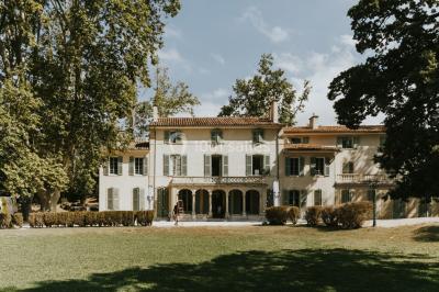 Vue aérienne d'une grande maison de style provençal avec des tables dressées pour un événement en extérieur.