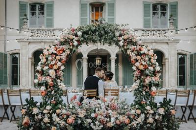 Vue aérienne d'une grande maison de style provençal avec des tables dressées pour un événement en extérieur.